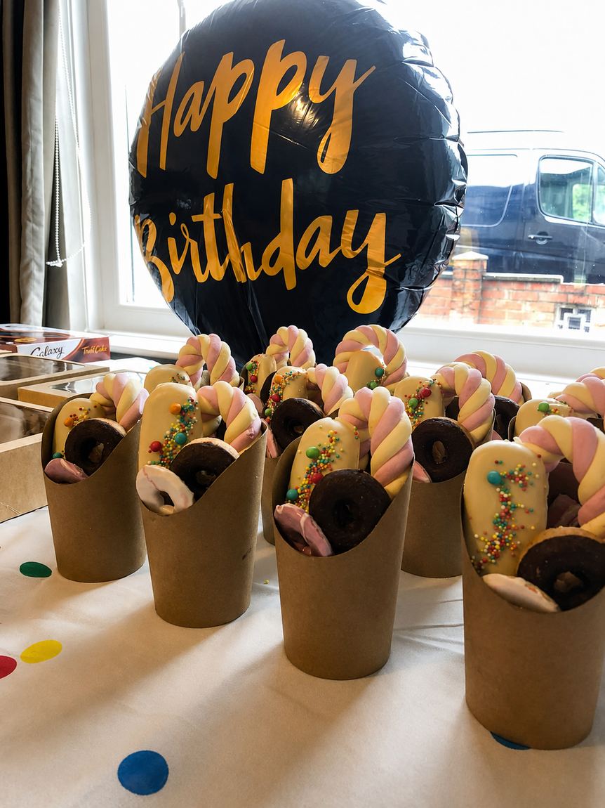 Sweet cups on a birthday table with a balloon behind